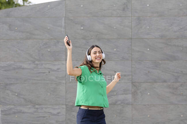 Donna felice che balla davanti al muro grigio — Foto stock