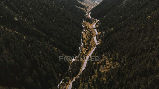 Aerial view of winding road stretching along river in autumn valley — Stock Photo
