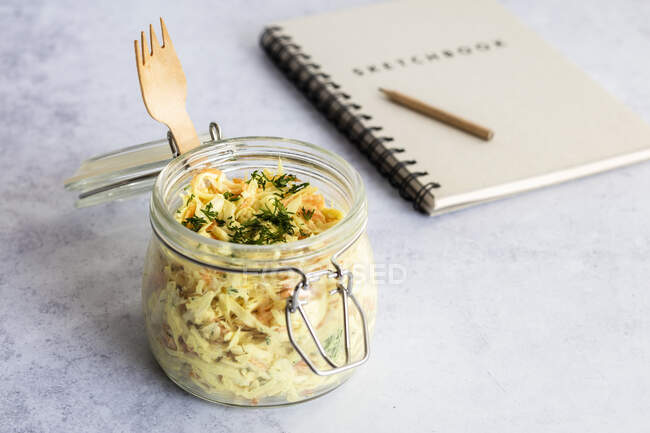 Jar of grated vegetable salad with note pad in background — Stock Photo