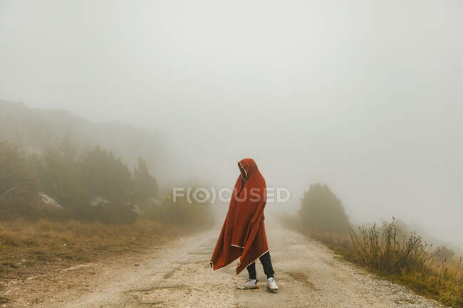 Joven cubierto de manta de pie en el camino - foto de stock