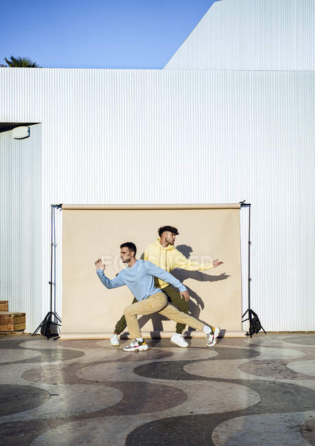 Male friends dancing in front of backdrop — Stock Photo