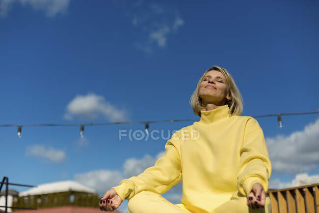 Sorrindo mulher adulta média com os olhos fechados meditando no telhado — Fotografia de Stock