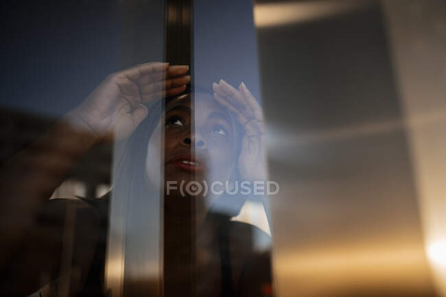 Молодая женщина смотрит через стекло — стоковое фото