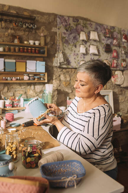 Mature female artist decorating flower pot at workshop — Stock Photo