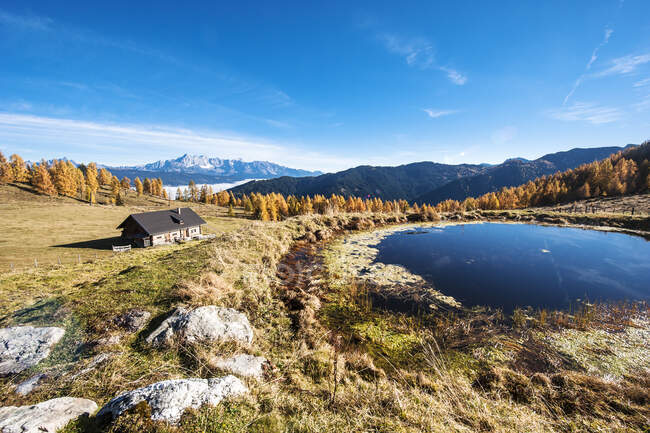 Покрита хатина, що стоїть перед маленьким альпійським озером восени. — стокове фото