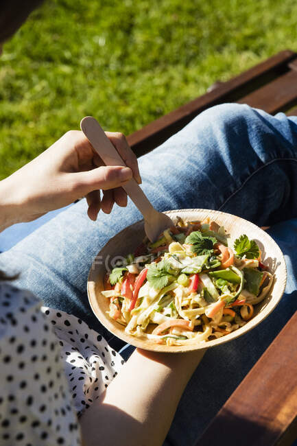 Mid section of woman eating bowl of raw vegan pad thai — Stock Photo
