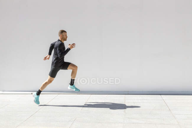 Sportsman running on footpath during sunny day — Stock Photo