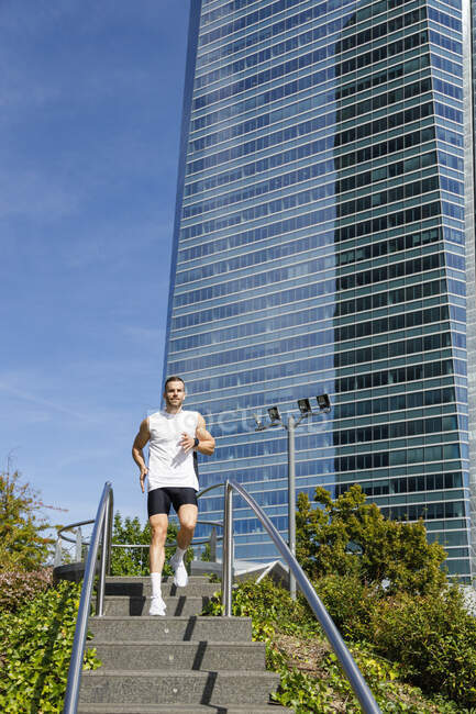 Male athlete running down on steps in city — Stock Photo