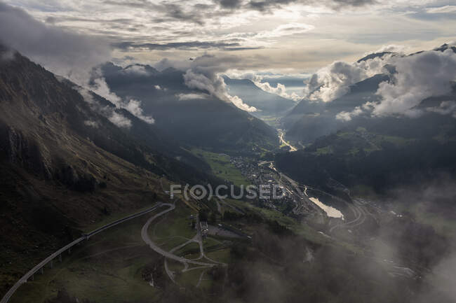 Suíça, Ticino, Airolo, vista dramática de Gotthard Pass e aldeia de montanha ao entardecer — Fotografia de Stock