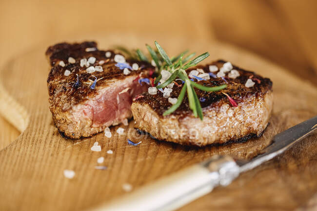 Nahaufnahme eines halbierten Fertigsteaks, das auf einer Holzoberfläche liegt — Stockfoto