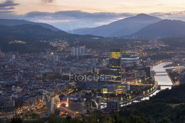 España, Vizcaya, Bilbao, Riverside city al atardecer - foto de stock