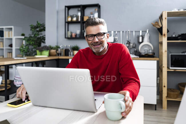 Man sitting with laptop and coffee cup at table — Stock Photo