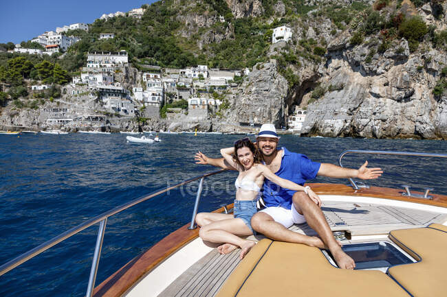 Улыбающаяся пара с протянутыми руками, сидящая в катерах — стоковое фото