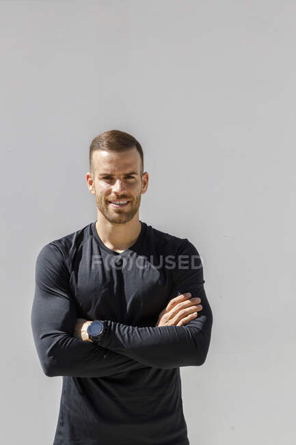 Lächelnder Sportler steht mit verschränkten Armen vor der Wand — Stockfoto