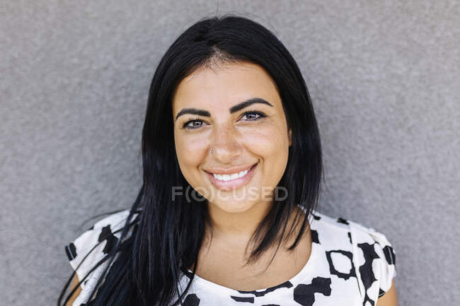 Schöne Frau lächelt vor grauem Hintergrund — Stockfoto