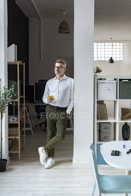 Uomo d'affari con cellulare che contempla in ufficio — Foto stock