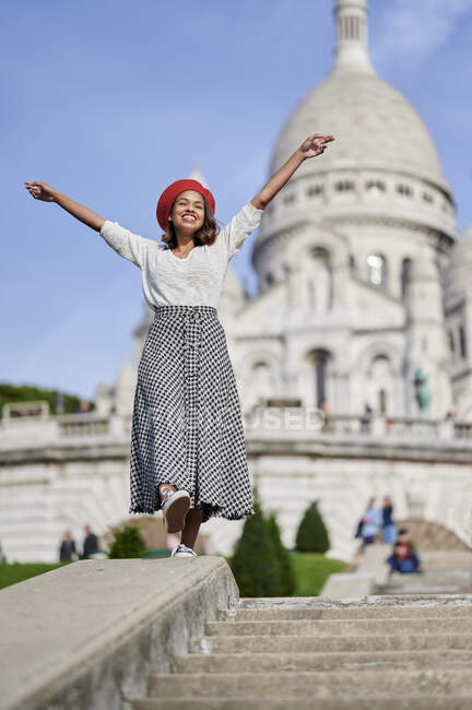 Посміхнена жінка з витягнутими руками стоїть у Базиліку - дю - Сакре - Кер (Монмартр, Париж, Франція). — стокове фото