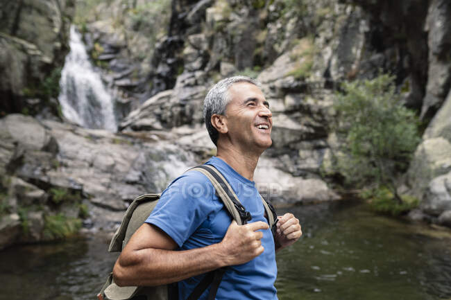 Feliz turista masculino con mochila en el bosque - foto de stock