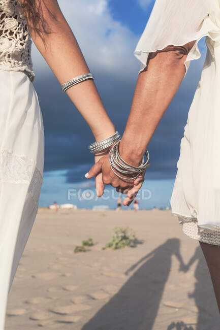 Reife Frau hält Hände von Teenagermädchen am Strand — Stockfoto