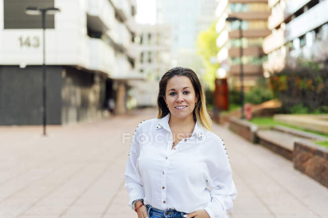Smiling woman on footpath in city — Stock Photo