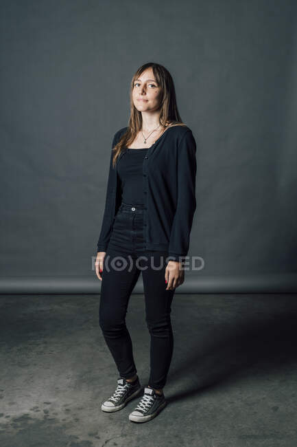 Donna in casuals nero in piedi di fronte a sfondo grigio — Foto stock