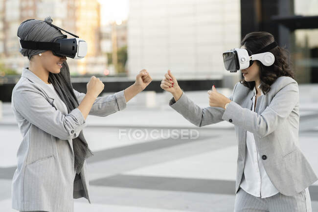 Молода бізнес-леді грає з колегою, носячи симулятор віртуальної реальності. — стокове фото