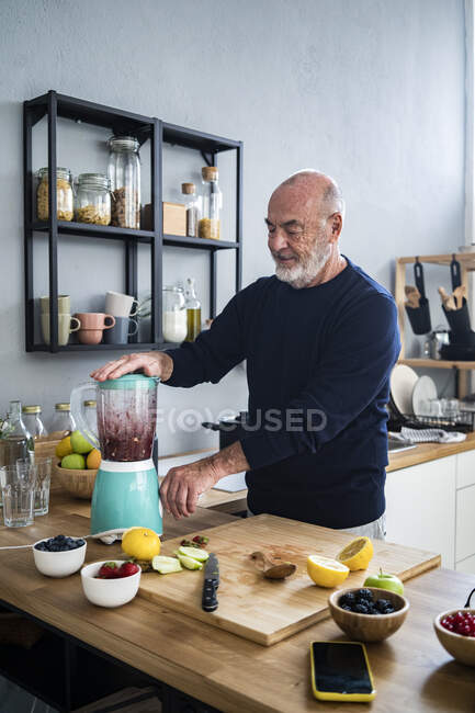 Senior man making smoothie in kitchen — one person, Food and drink - Stock  Photo | #527926058