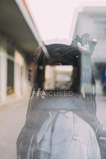 Mulher com travas de cabelo atrás da parede de vidro — Fotografia de Stock