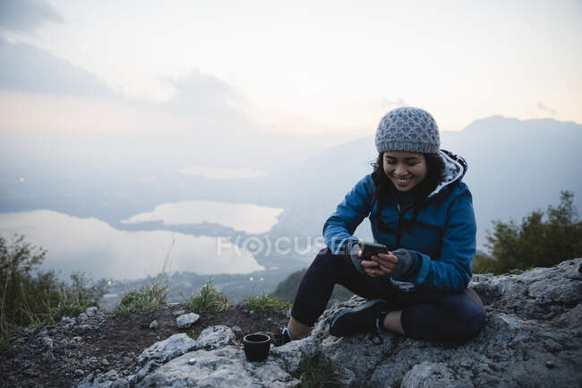 Joyeux message texte jeune femme par téléphone intelligent sur la montagne — Photo de stock