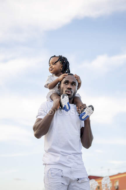Homme ronronnant tout en portant sa fille sur les épaules — Photo de stock