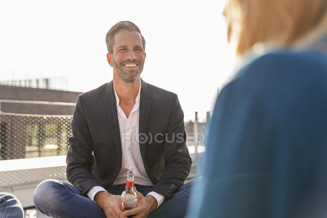 Усміхнений бізнесмен випиває з колегою на терасі. — стокове фото
