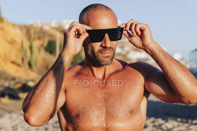 Homme sans chemise portant des lunettes de soleil pendant le coucher du soleil — Photo de stock
