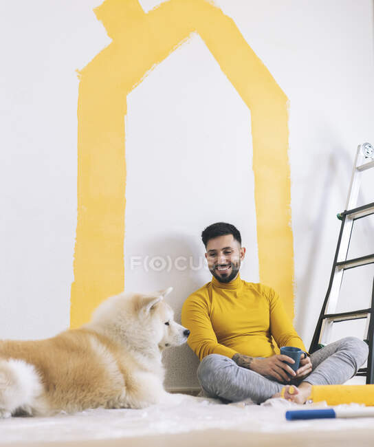 Улыбающийся мужчина смотрит на собаку Акита в гостиной — стоковое фото