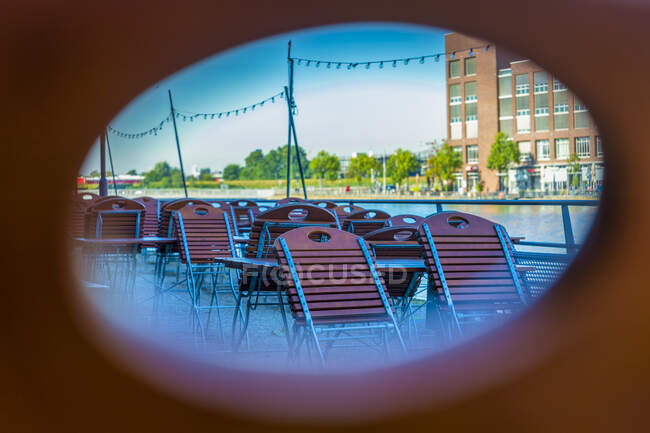 Пустые стулья и столы на террасе ресторана видны через овальное отверстие — стоковое фото