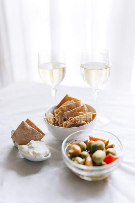 Dois copos de vinho branco e tigela de biscoitos com molho de mergulho — Fotografia de Stock