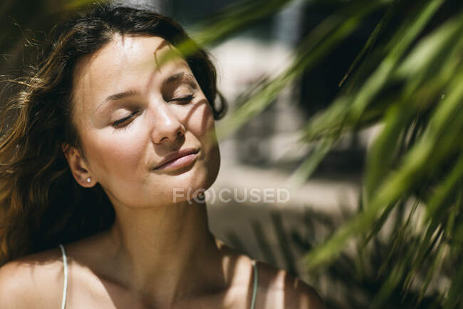 Mujer adulta con los ojos cerrados durante el día soleado - foto de stock