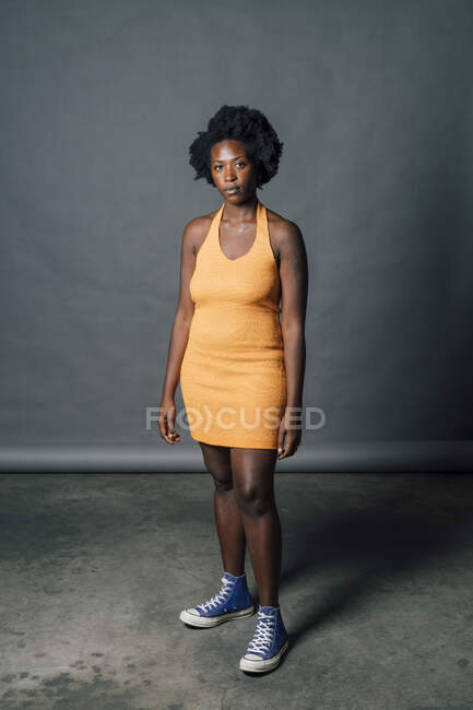 Giovane donna sicura di sé in abito arancione di fronte a sfondo grigio — Foto stock