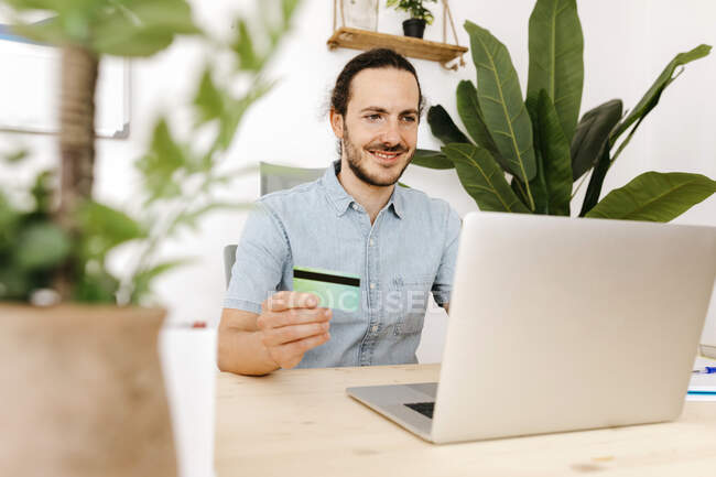 Businessman with credit card and laptop at office — Stock Photo