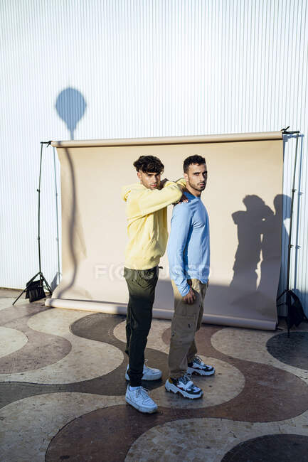 Male friends standing together by backdrop — Stock Photo