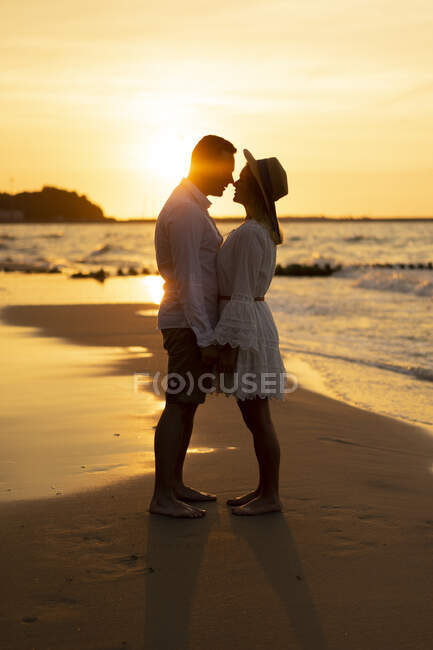 Freund reibt Nase mit Freundin am Strand bei Sonnenuntergang — Stockfoto