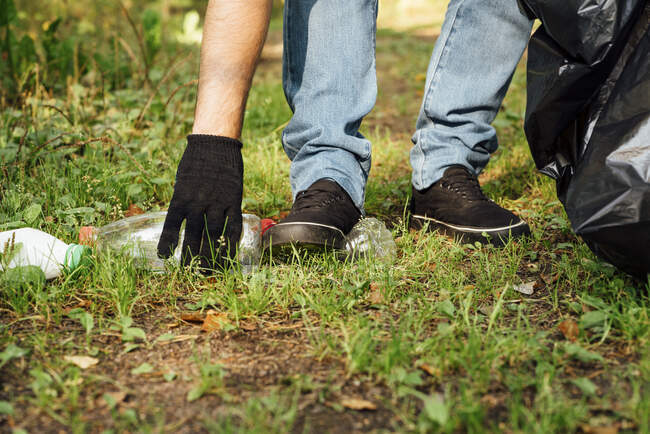 Ativista do sexo masculino coletando garrafas na floresta — Fotografia de Stock