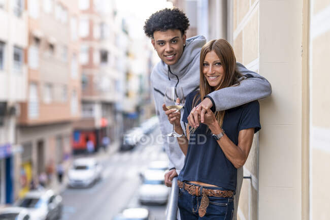 Молодой человек с рукой вокруг зрелой женщины, стоящей на балконе — стоковое фото