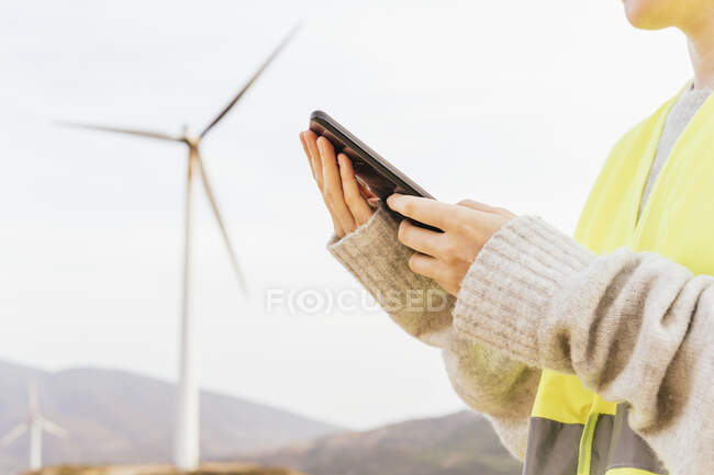Жінка користується мобільним телефоном на вітровій фермі. — стокове фото