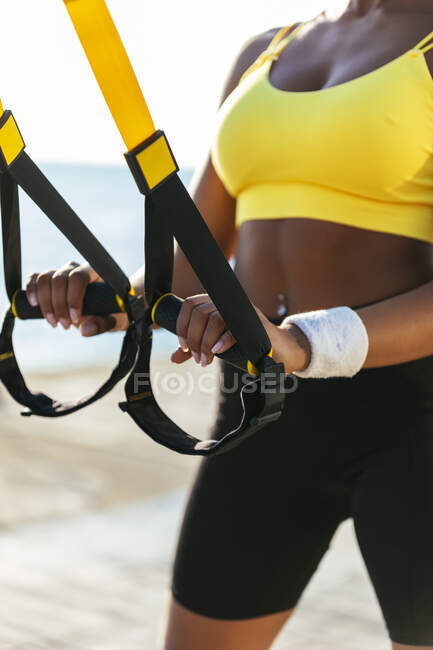 Giovane atleta femminile che tiene cinghie di sospensione nella giornata di sole — Foto stock