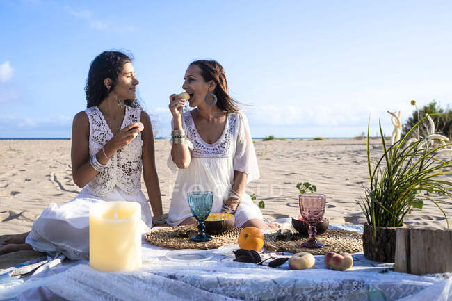 Adolescente regardant un ami féminin ayant de la nourriture sur la plage — Photo de stock