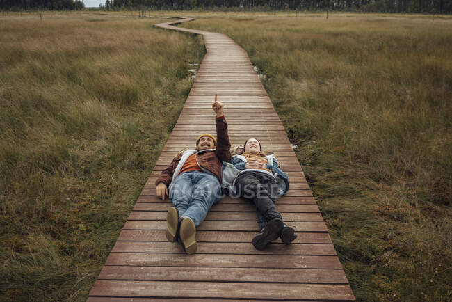 Uomo che punta mentre sdraiato con la donna sul ponte pedonale — Foto stock