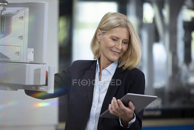 Femme d'affaires blonde avec tablette numérique travaillant dans l'usine — Photo de stock
