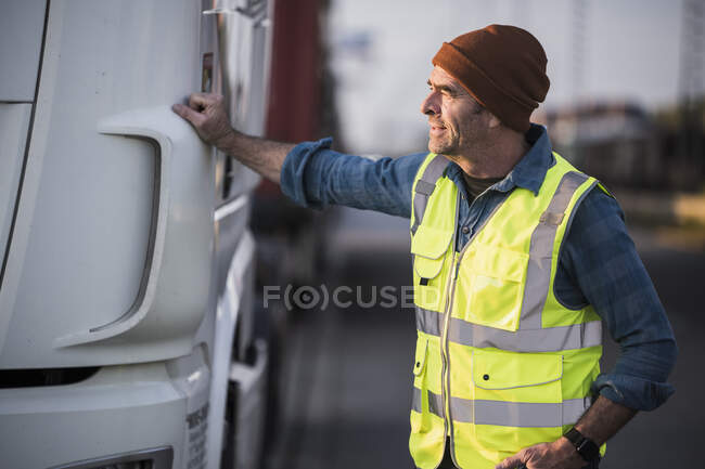 Camionista sorridente maschio con mano in tasca che cammina sulla strada al molo — Foto stock