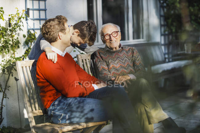 Homme parlant à l'oreille du fils par son père sur le banc — Photo de stock