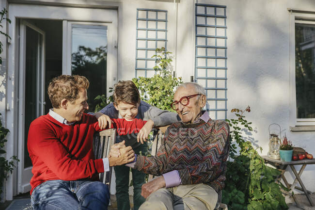 Улыбающийся мужчина держит сына за руку на заднем дворе — стоковое фото